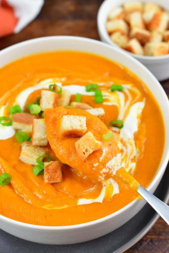 spooning out sweet potato soup out of a bowl