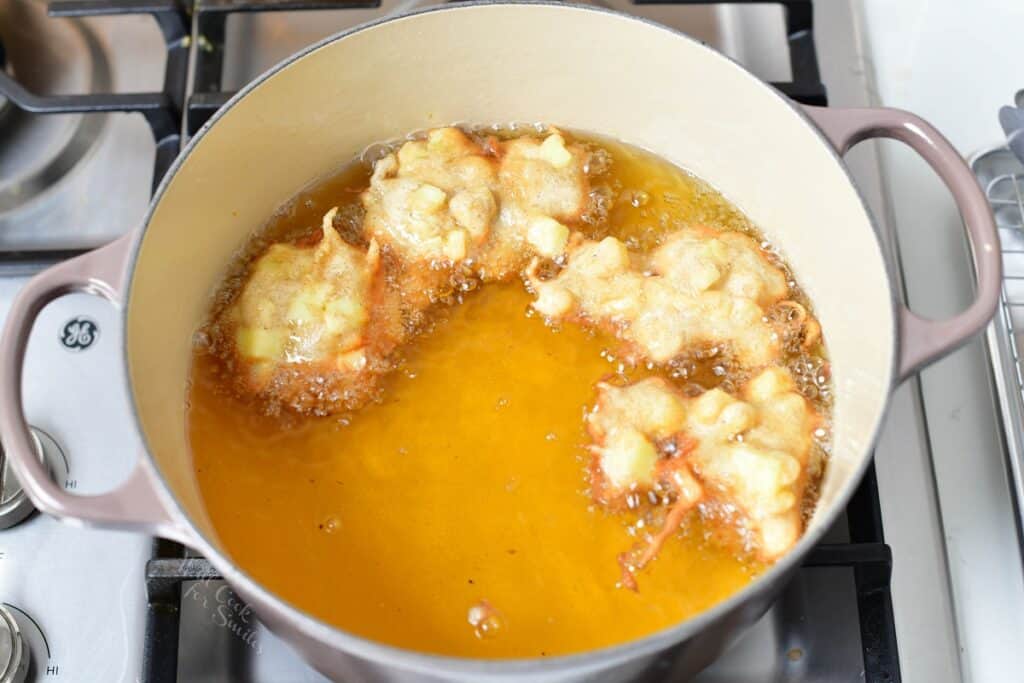 apple fritters frying in oil in Dutch oven
