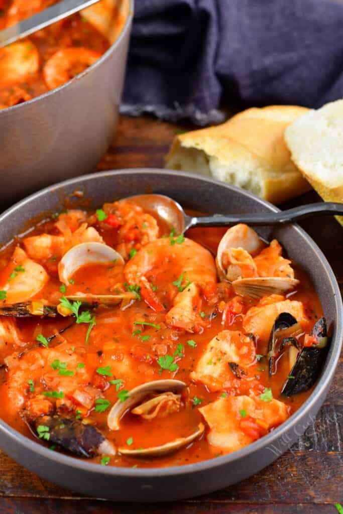 Cioppino in a grey bowl with bread next to it