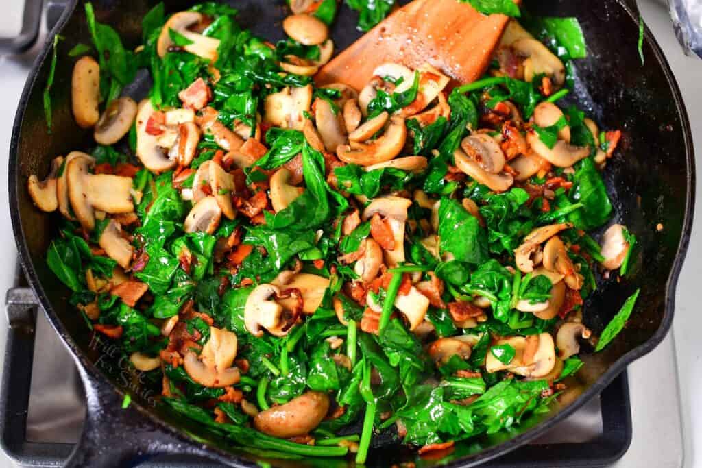 spinach bacon and mushrooms sautéed in a skillet