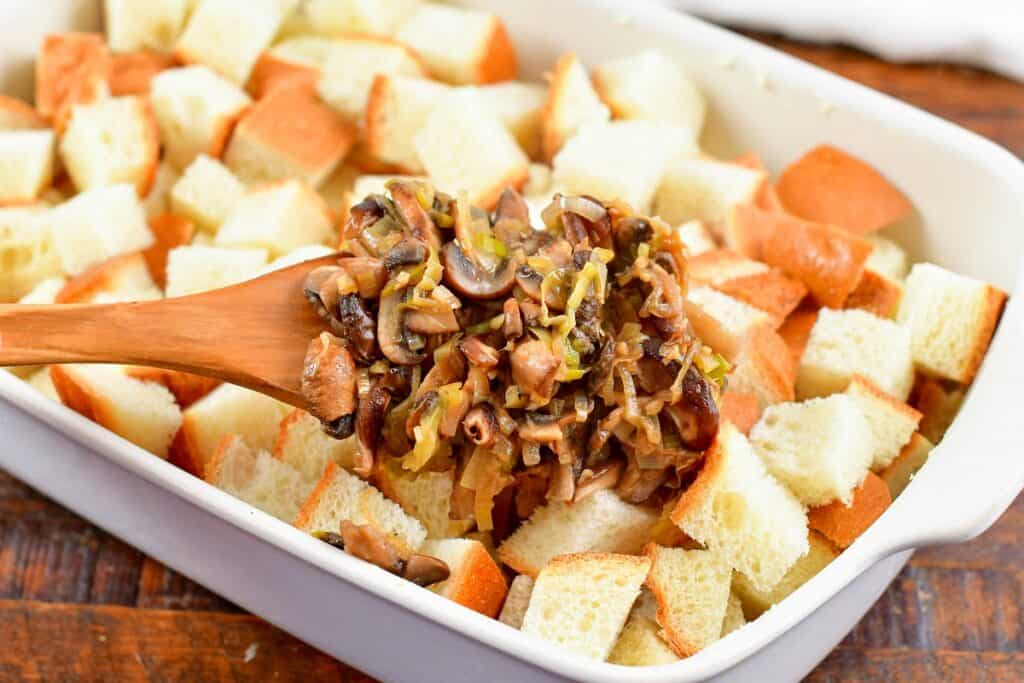 adding sautéed vegetables to the bread in a pan