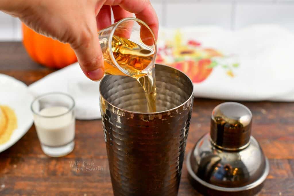 adding spiced rum to the cocktail shaker