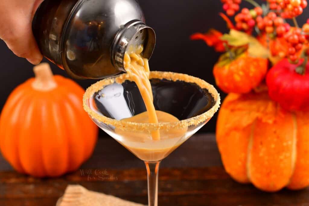 pouring in pumpkin pie martini into the martini glass