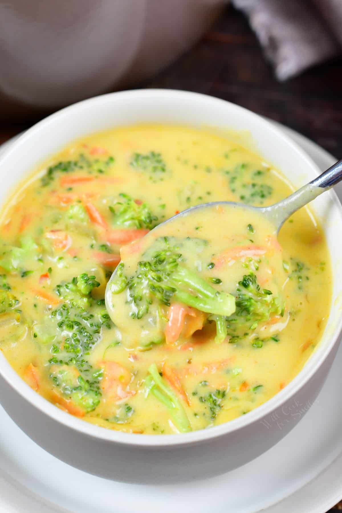 spooning some of the broccoli cheese soup from a bowl