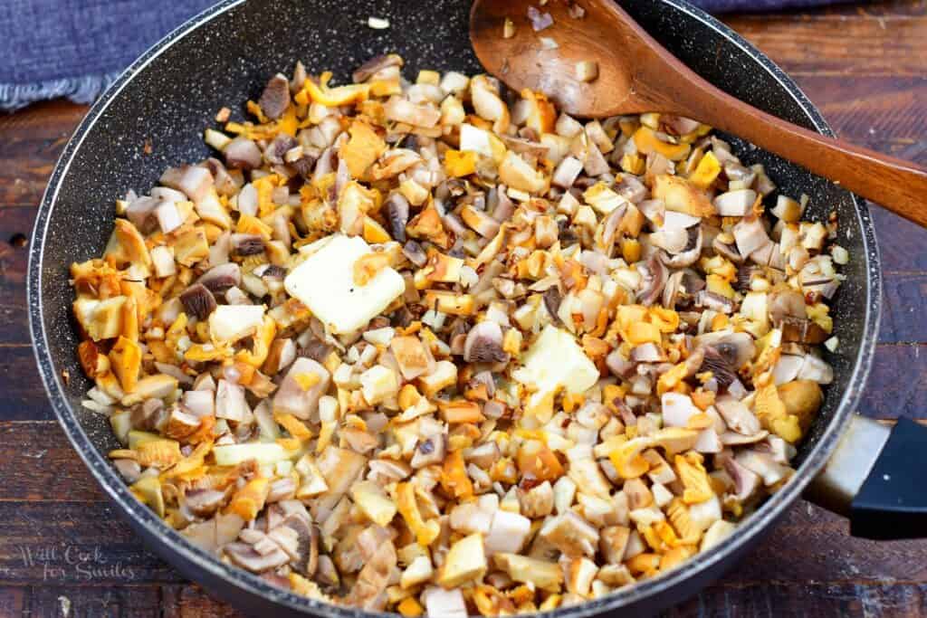 adding butter to the mushrooms in the cooking pan