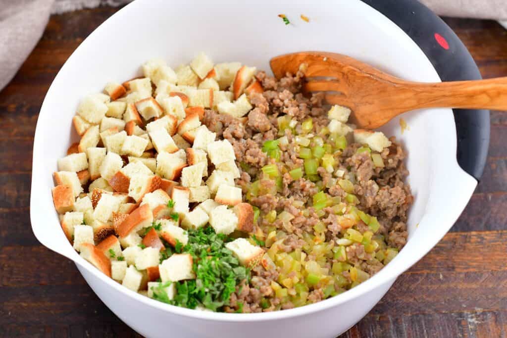 bread sausage herbs and veggies in a mixing bowl
