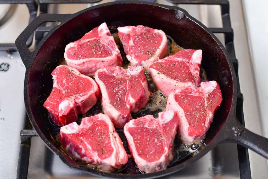 lamb chops added to the cast iron skillet to cook