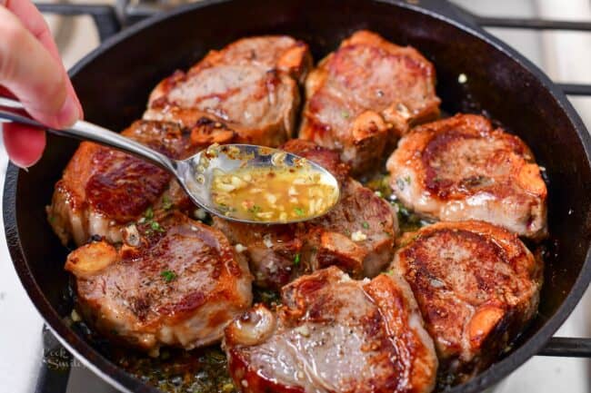 spreading melted butter sauce over the lamb in the skillet