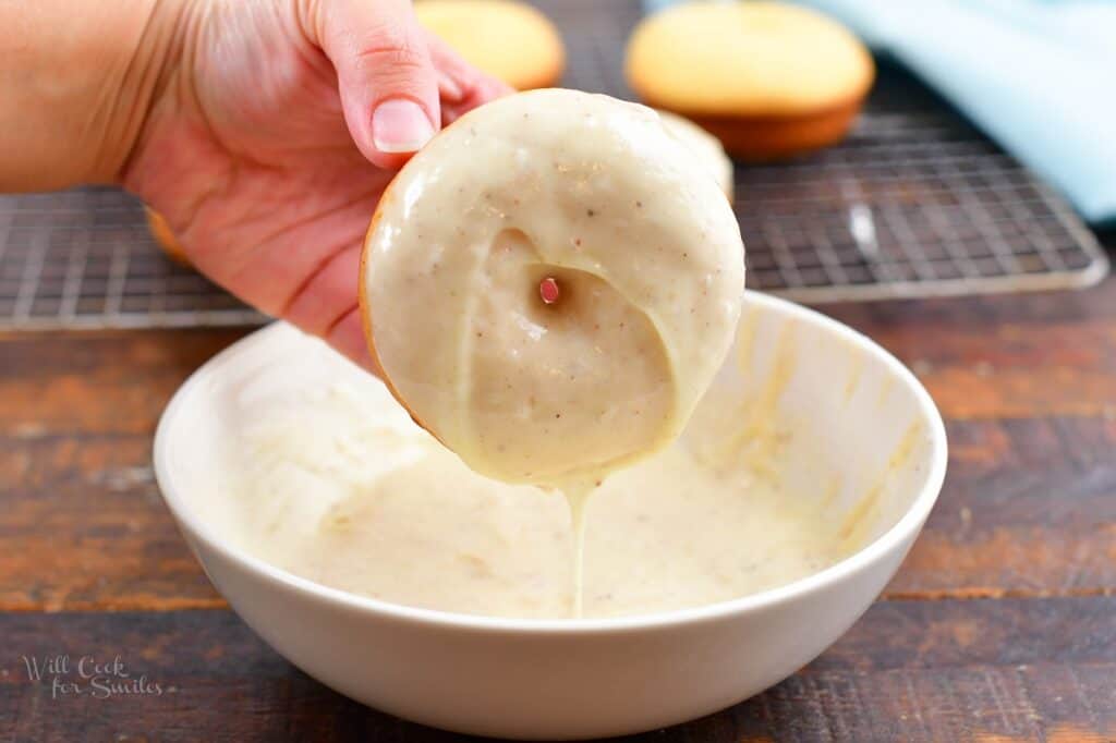 dipping a baked donut into eggnog glaze