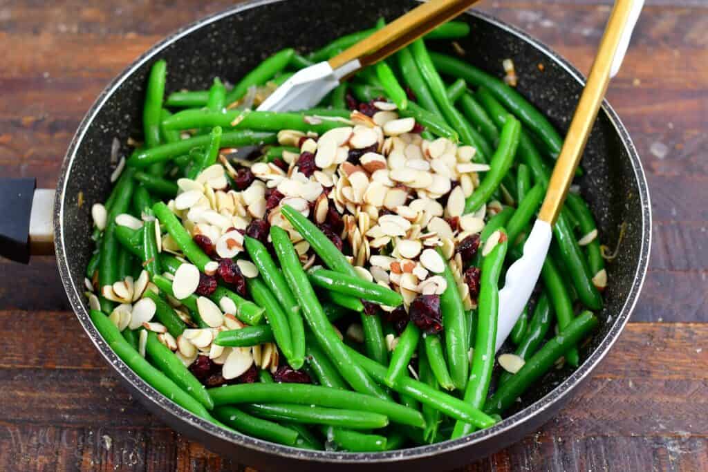 green beans in a pan with cranberries and almonds added