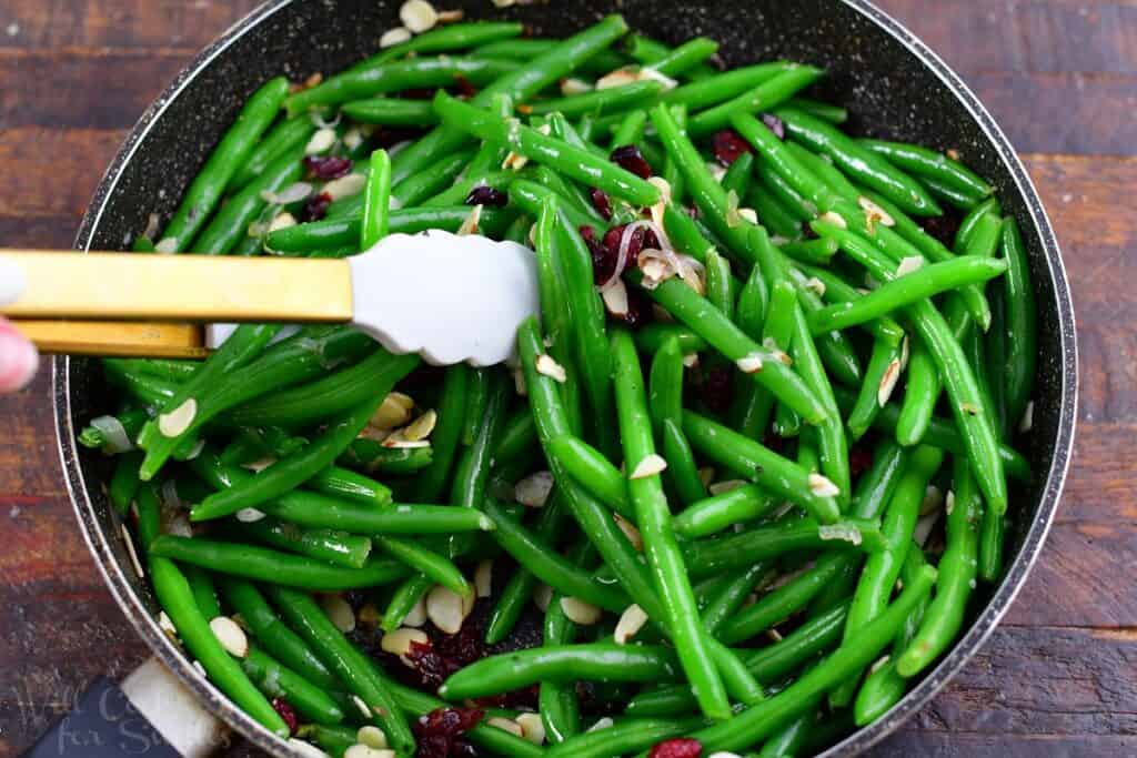 mixing green beans with cranberries and almonds
