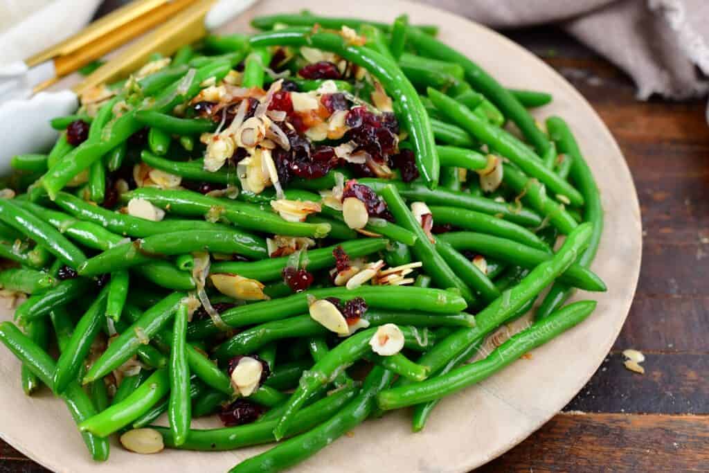 closeup of green beans on a plate with cranberries and almonds