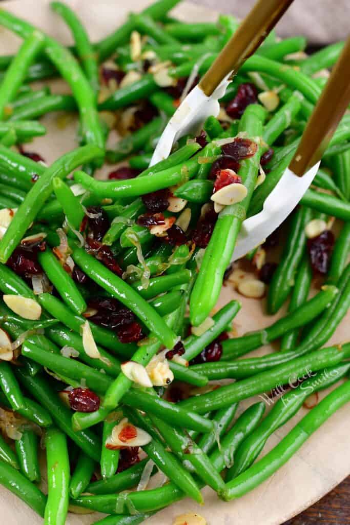 scooping green beans with gold metal tongs