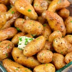 side view of roasted potatoes in a baking dish with butter and herbs