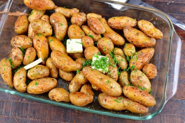 roasted fingerling potatoes in a glass roasting pan with butter and herbs