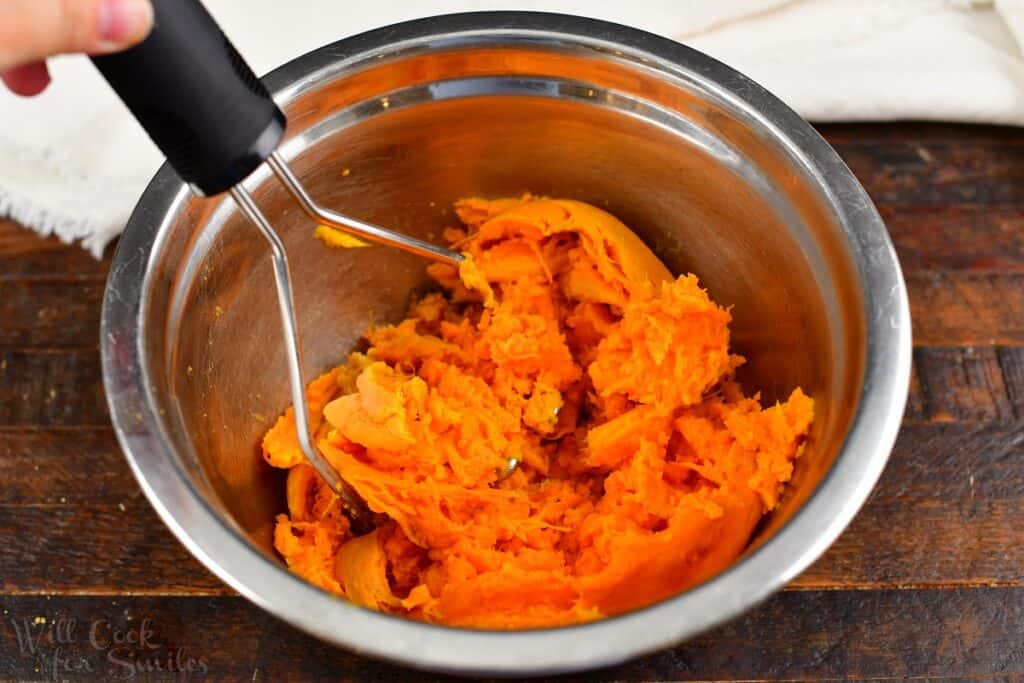 mashing sweet potatoes with a potato masher