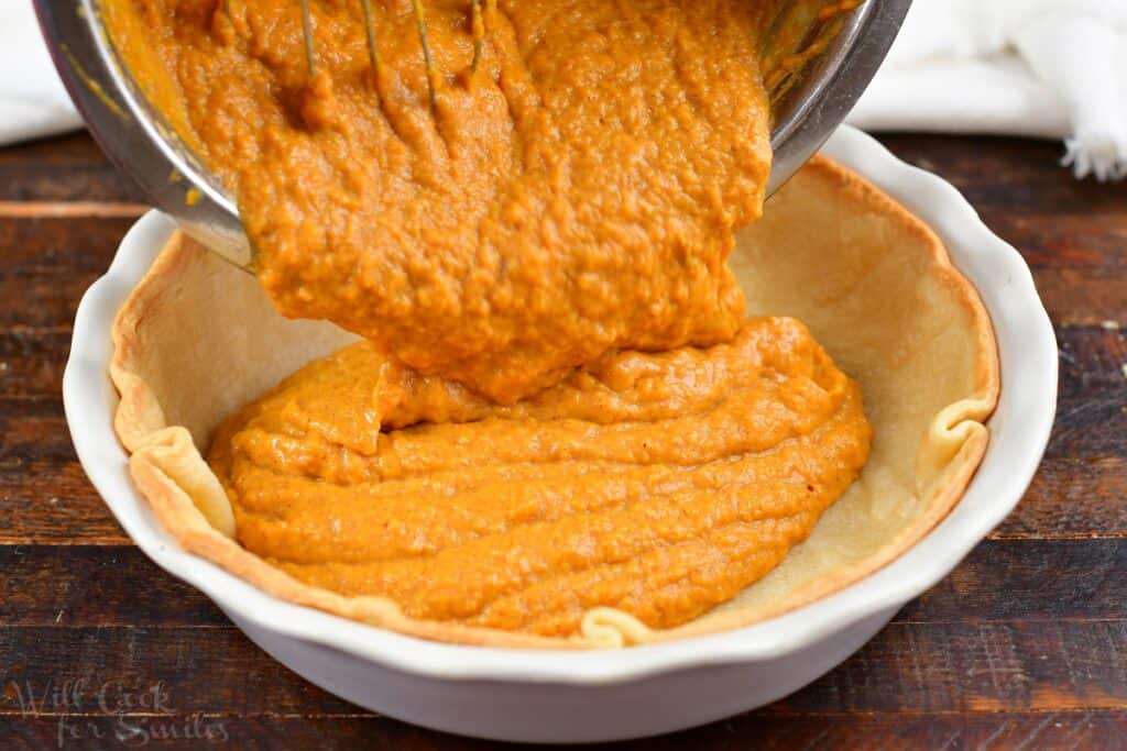 pouring sweet potato pie filling into a pie shell
