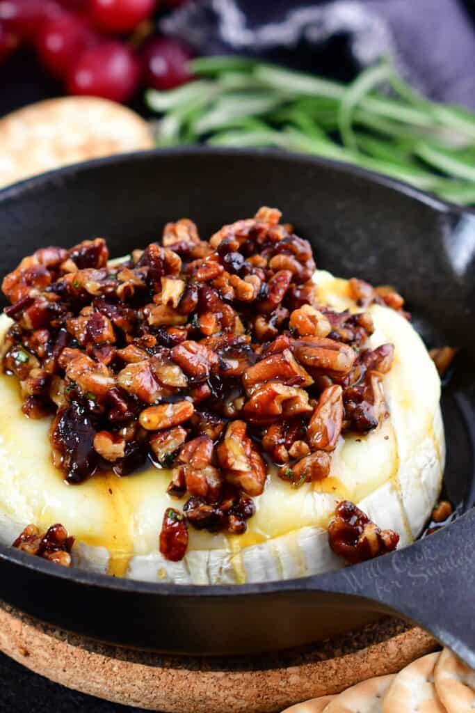 closeup of baked brie topped with pecans and honey