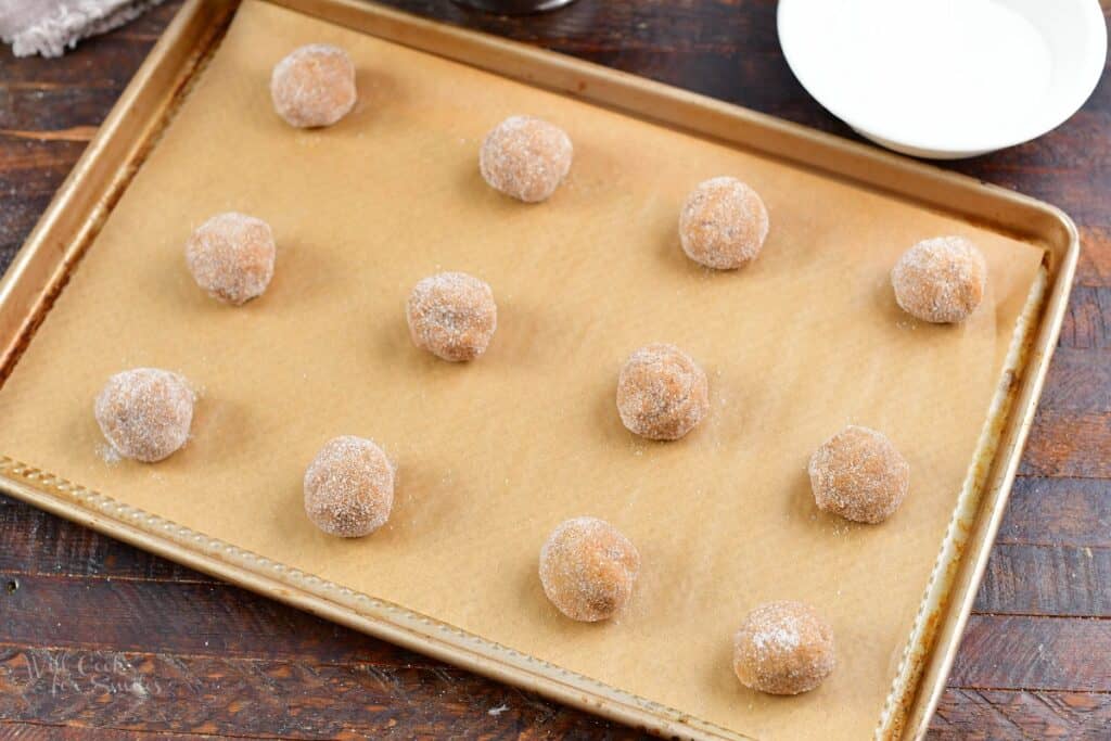 balls of cookie dough covered in sugar on the baking sheet