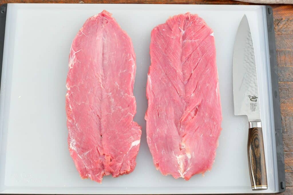 pork tenderloin butterflied on the cutting board with a knife