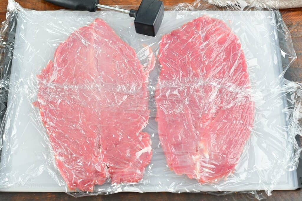 pork tenderloin opened on the cutting board with plastic on it