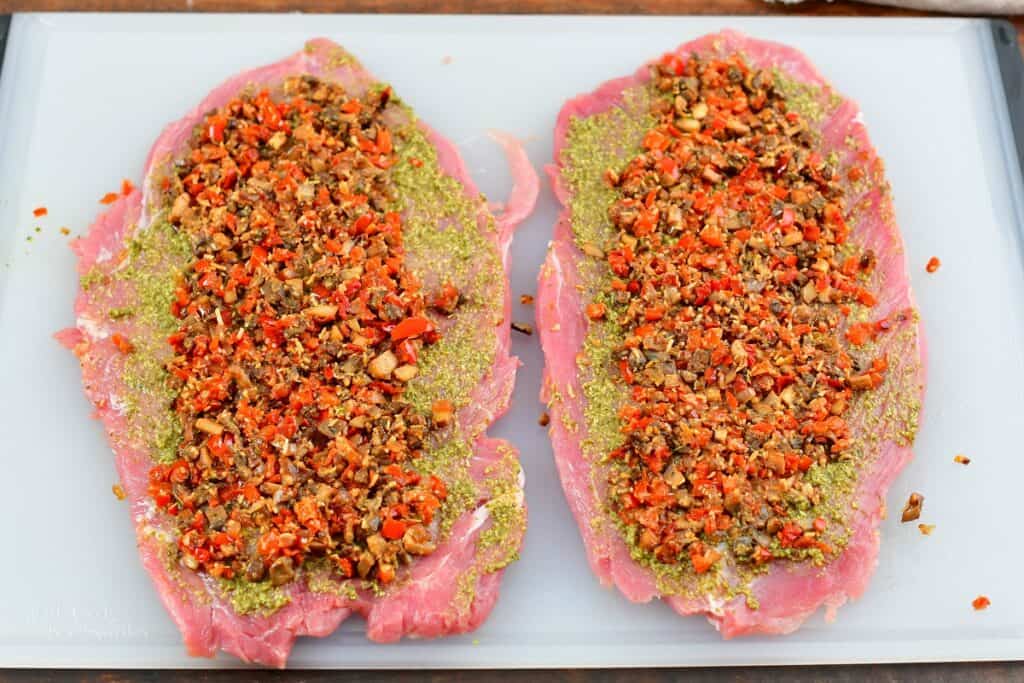 open pork tenderloin with stuffing spread on it