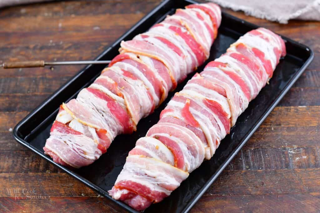 pork tenderloin wrapped in bacon on the baking sheet