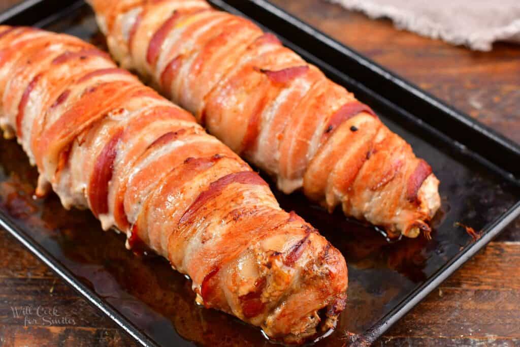 stuffed pork tenderloin in bacon cooked on black sheet pan