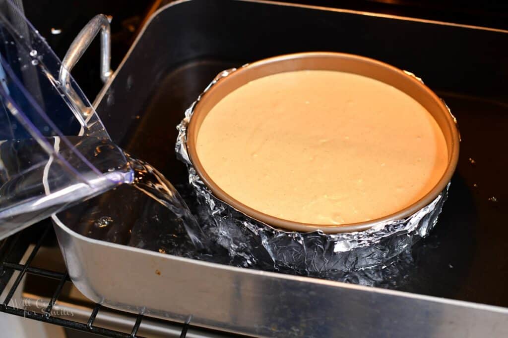 pouring water into the roasting pan with the cheesecake pan in it for water bath