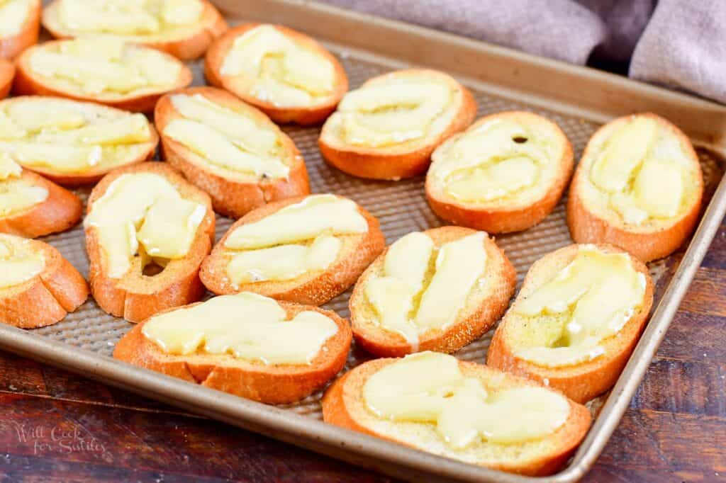 crostini on a baking sheet with melted Brie