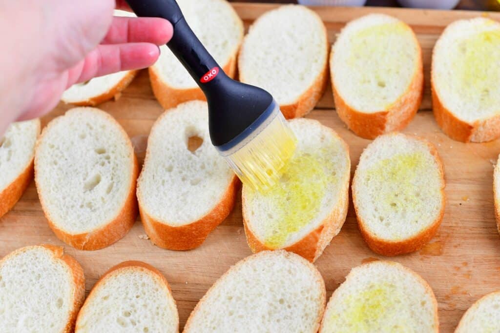 brushing slices of baguette with olive oil