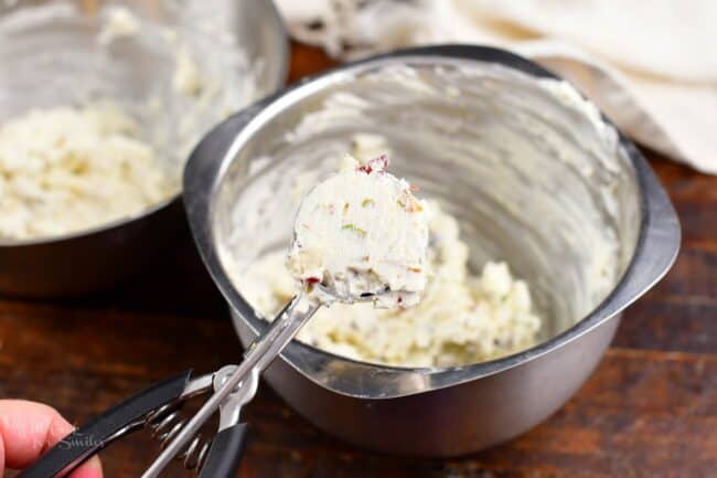 scooping out cream cheese mixture with a cookie scoop