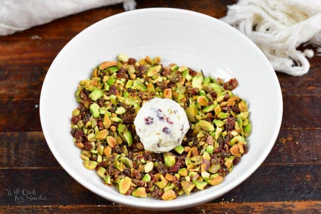 cheese ball in a bowl with pecan and cranberry topping