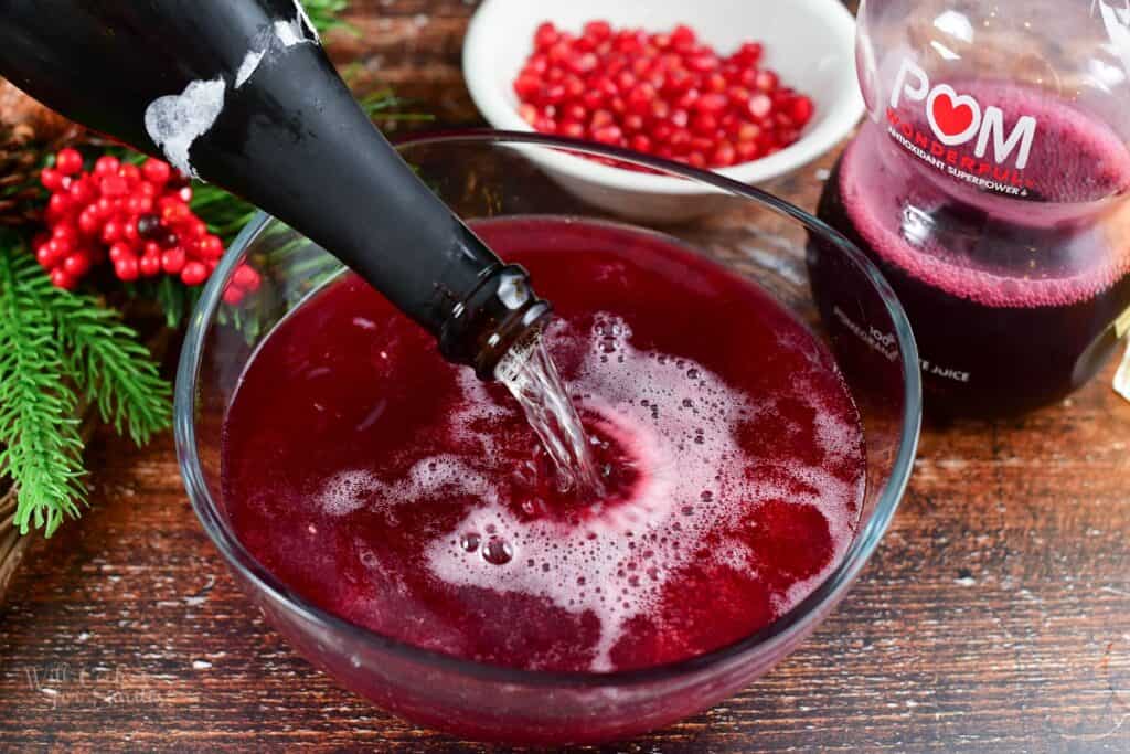 adding champagne to the punch bowl