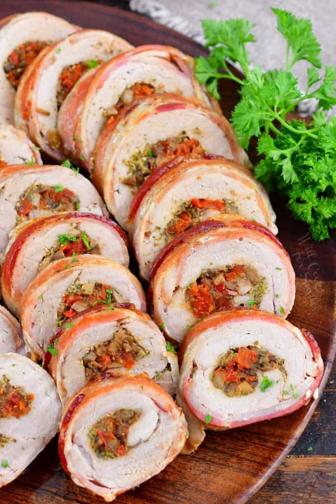sliced stuffed pork tenderloin stacked side by side on a platter