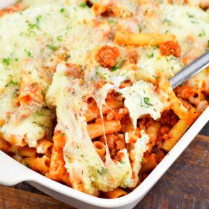 closeup of scooping baked ziti out of the baking dish