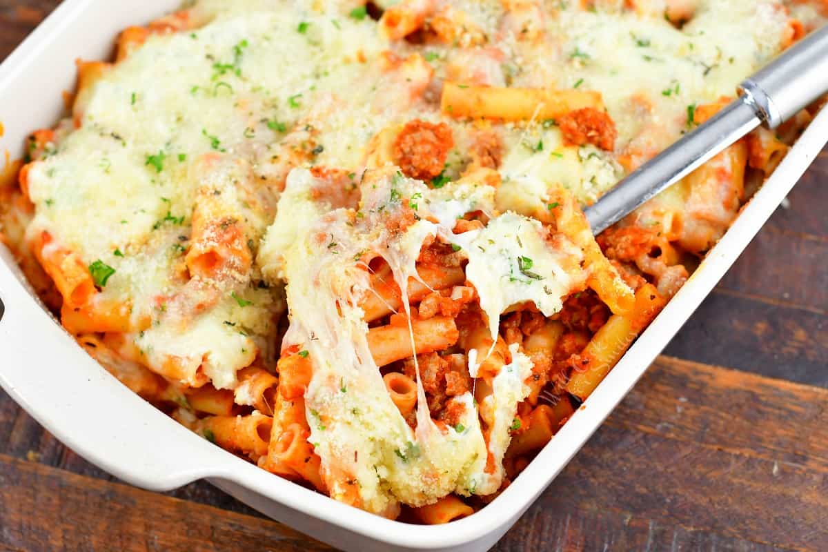 closeup of scooping baked ziti out of the baking dish