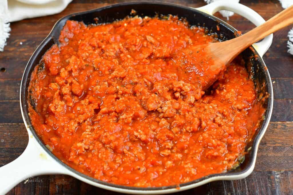 meat sauce in a cooking pan and wooden spatula