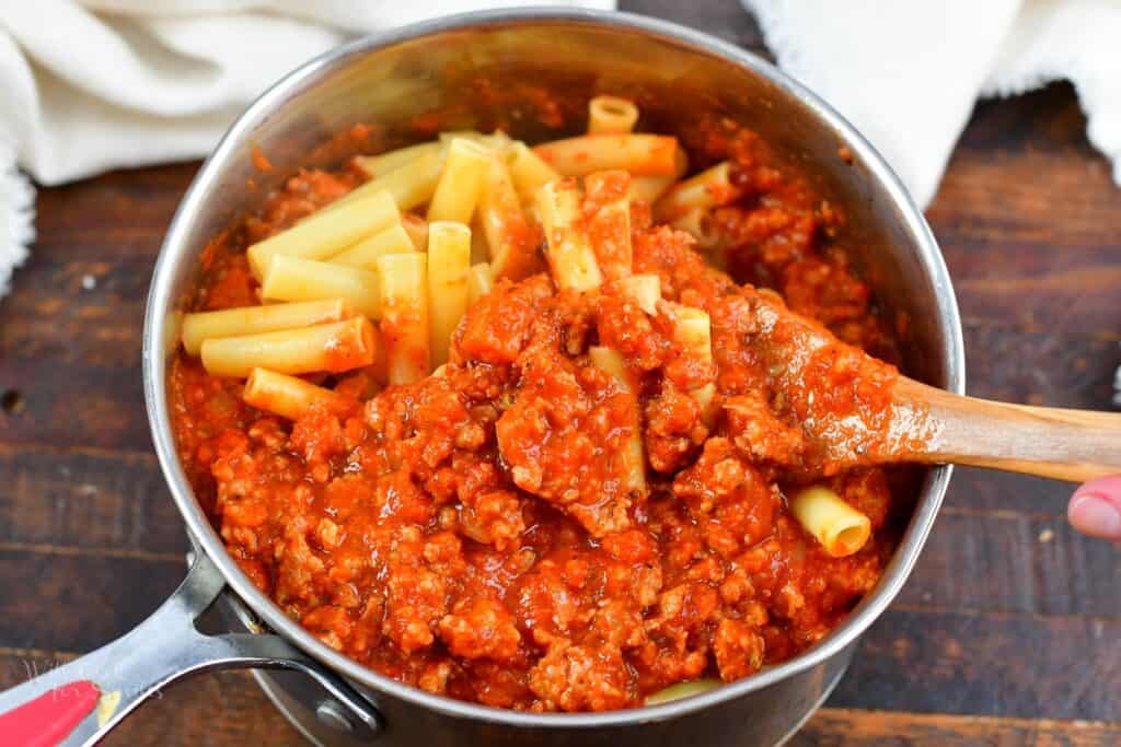 mixing cooked ziti with meat sauce