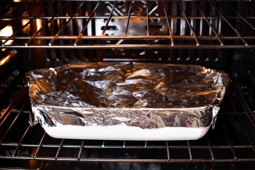 baking dish covered with aluminum foil in the oven
