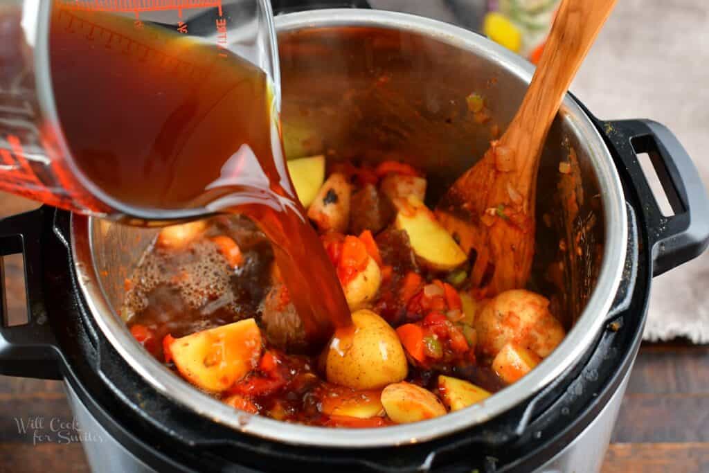 adding the beef stock to the vegetables and beef