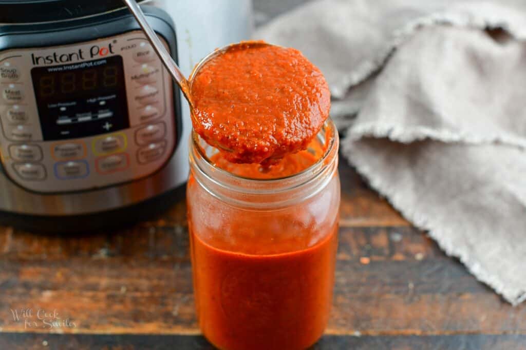 ladling the sauce into glass jar
