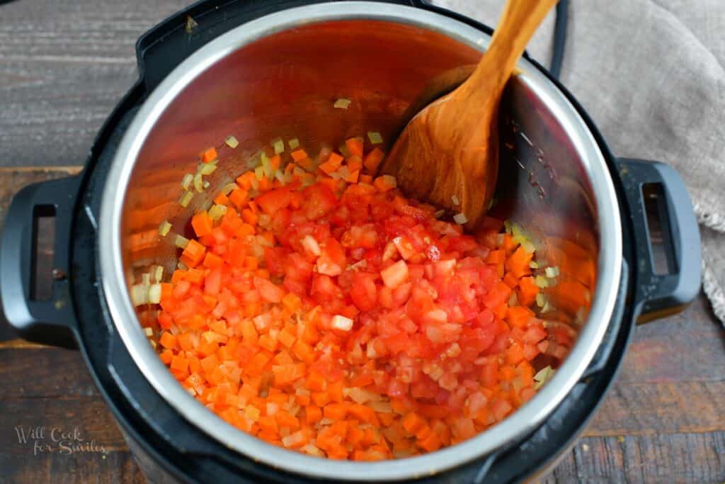 adding tomatoes to cooked onion and carrots