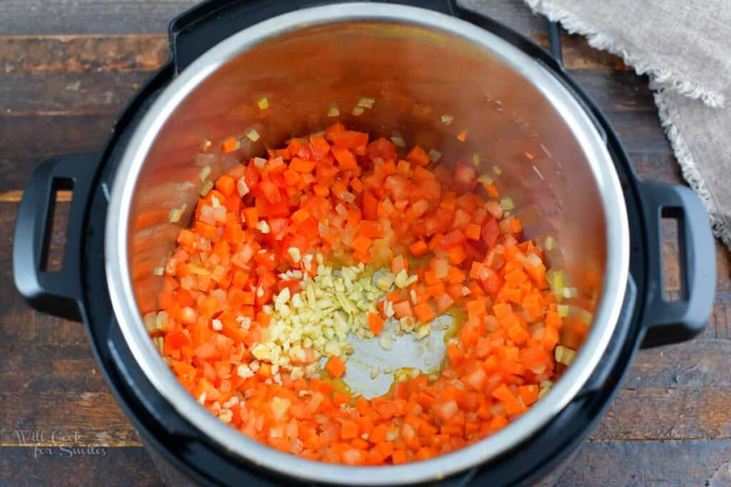 adding minced garlic to the vegetables in the pot