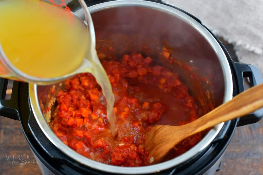 adding chicken stock to the pot with vegetables