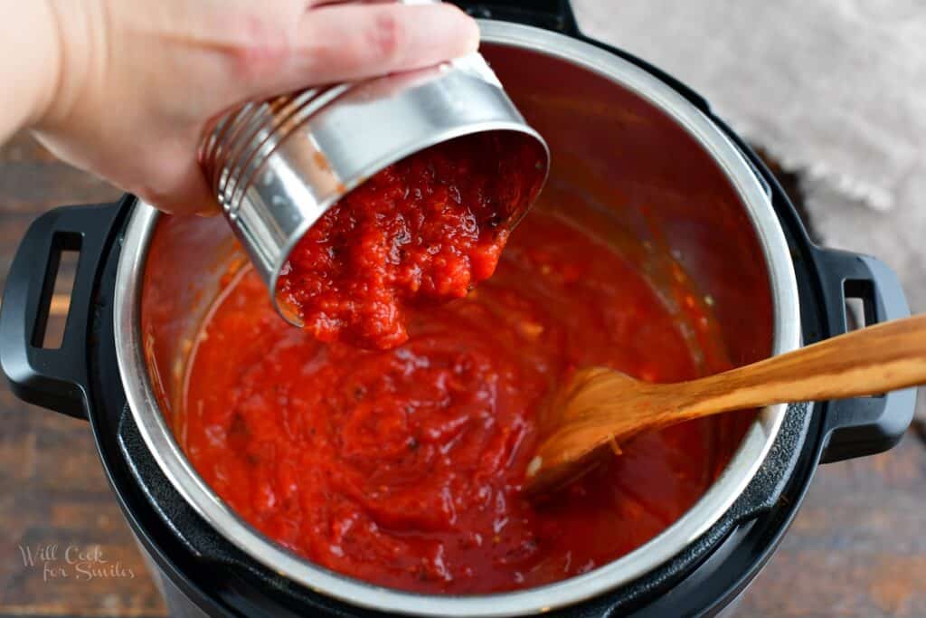 adding crushed tomatoes to the pot