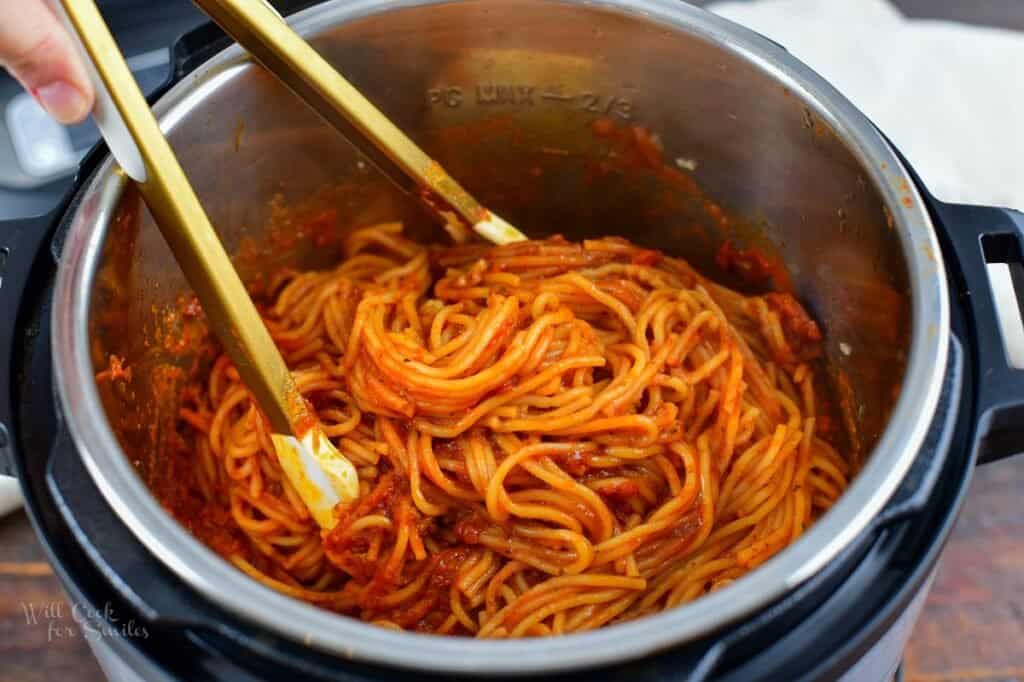 stirring the cooked pasta in sauce in the instant pot