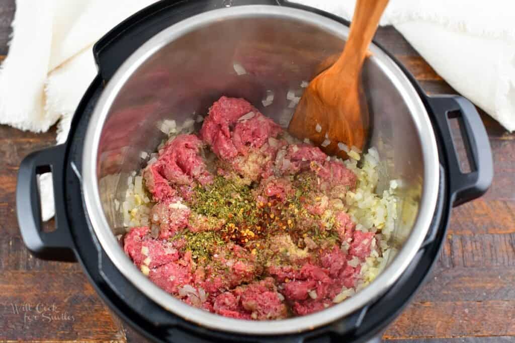 ground beef in the pot with seasoning and onions