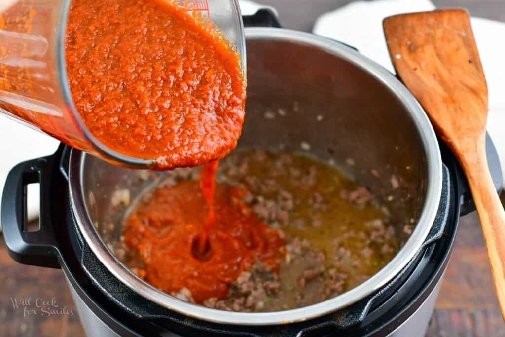 pouring in some pasta sauce over meat mixture