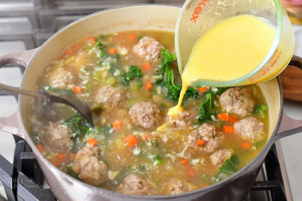 pouring in whisked egg into stirring soup